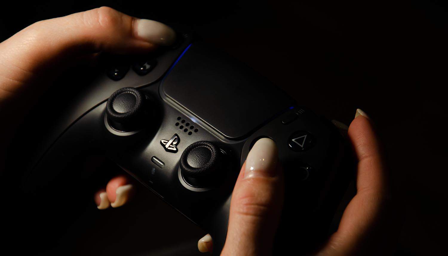 Hand holding PlayStation 5 controller showing breached helpdesk system sending malware