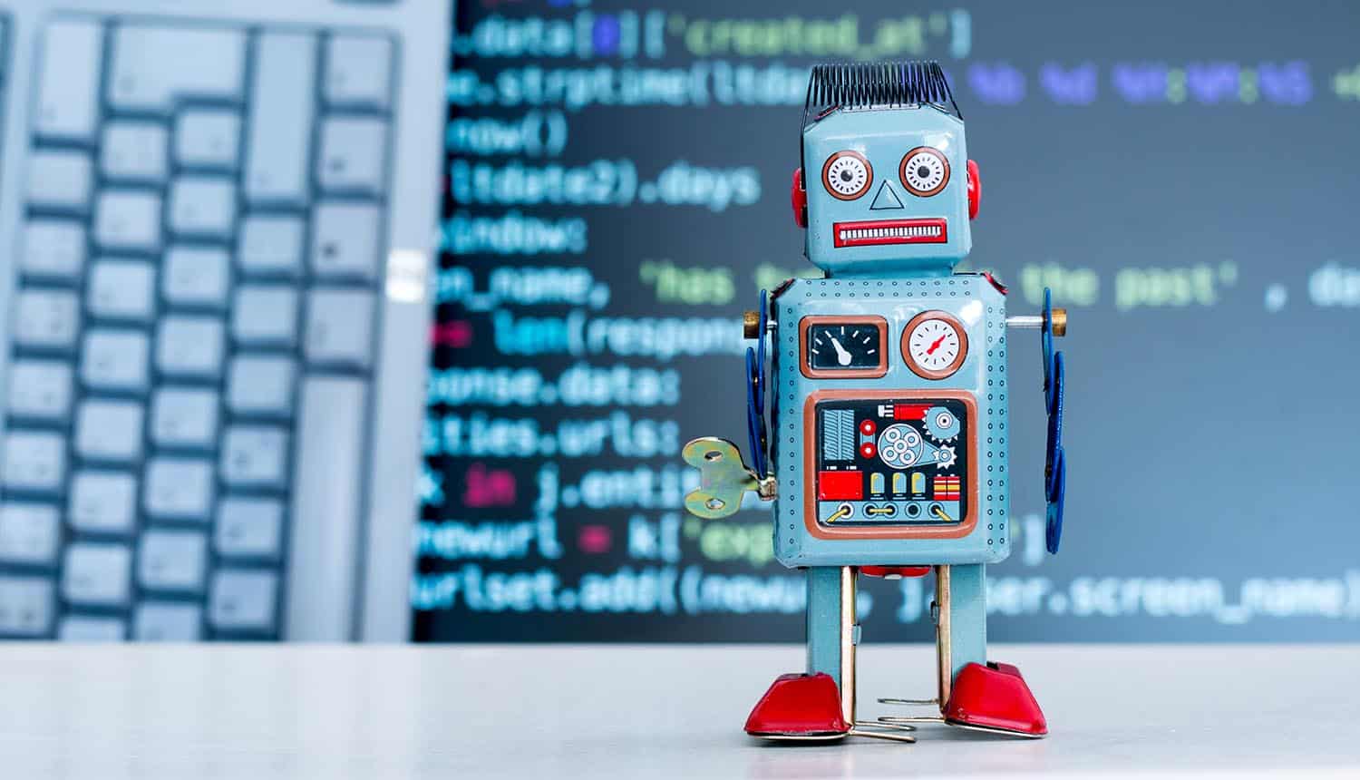 Toy robot standing in front of keyboard showing AI chatbots