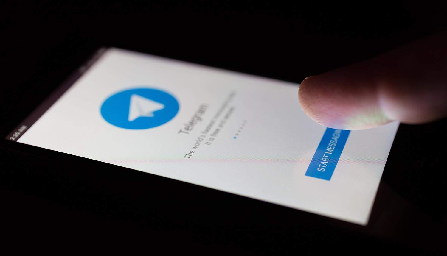 Smartphone in the dark displaying Telegram messenger showing cybercrime ecosystem
