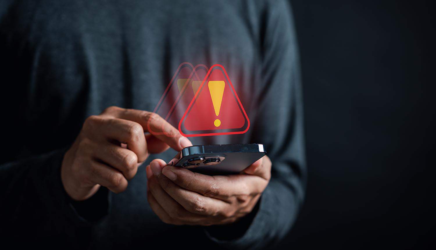 System warning sign on mobile phone showing commercial spyware exploiting zero-days