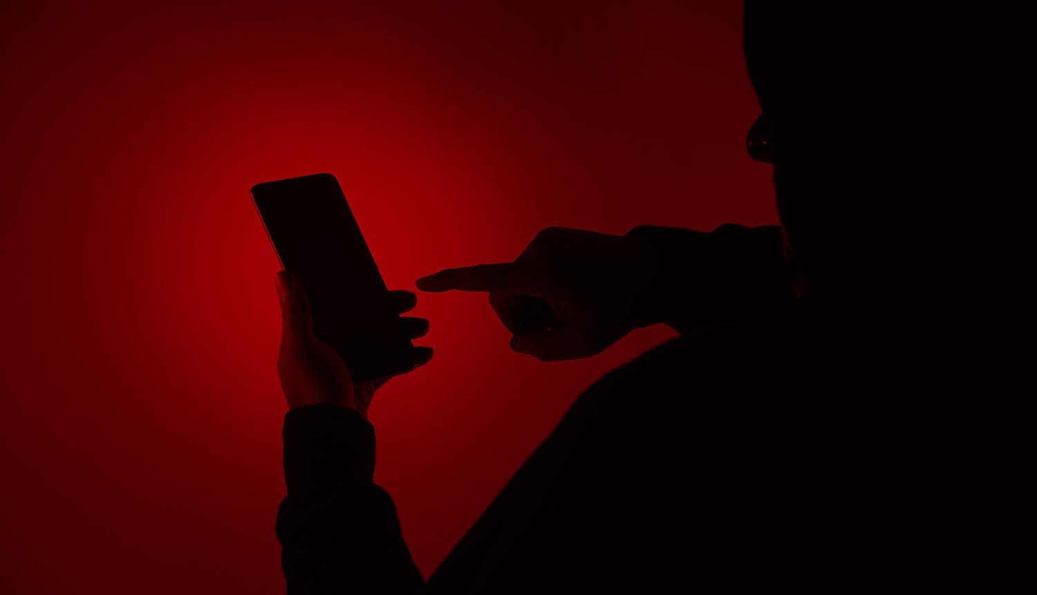 Hacker holding smartphone showing spyware in Android apps