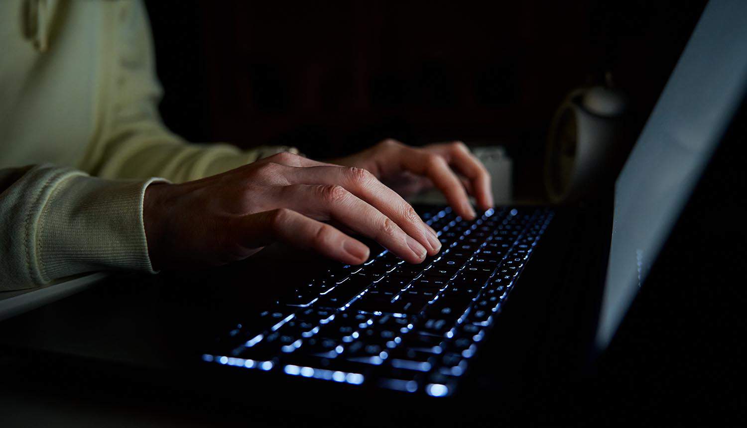 Woman typing on laptop keyboard showing hacking forum data leak