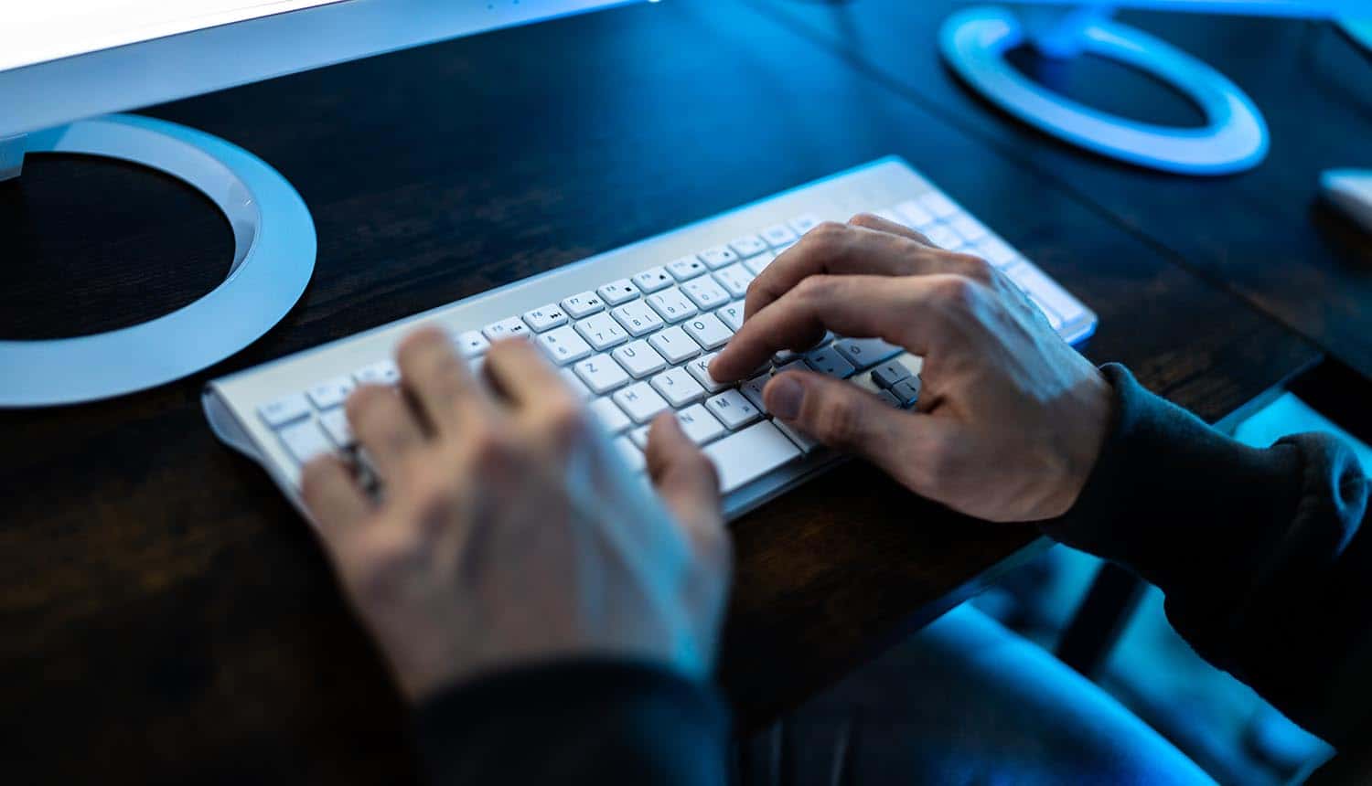 Hacker working on keyboard showing cybercriminals and social engineering