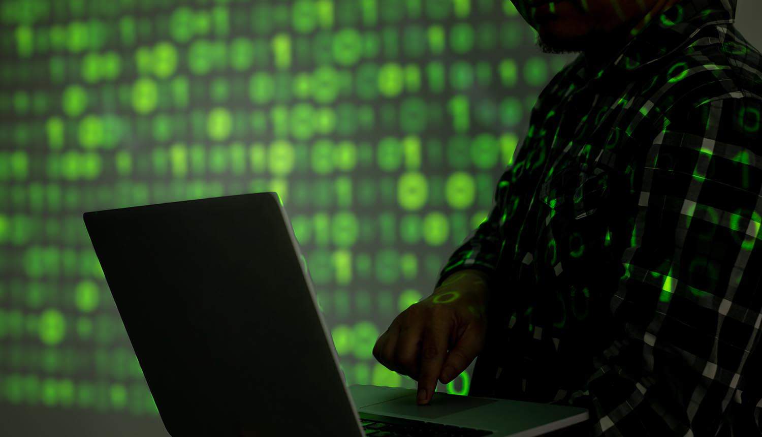Hacker holding laptop showing cyber attacks in Israel-Hamas conflict