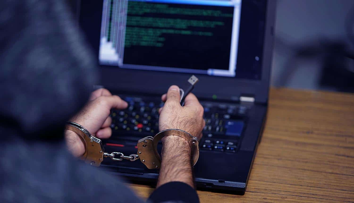 Hacker in handcuffs showing law enforcement operation on dark web site of ransomware gang