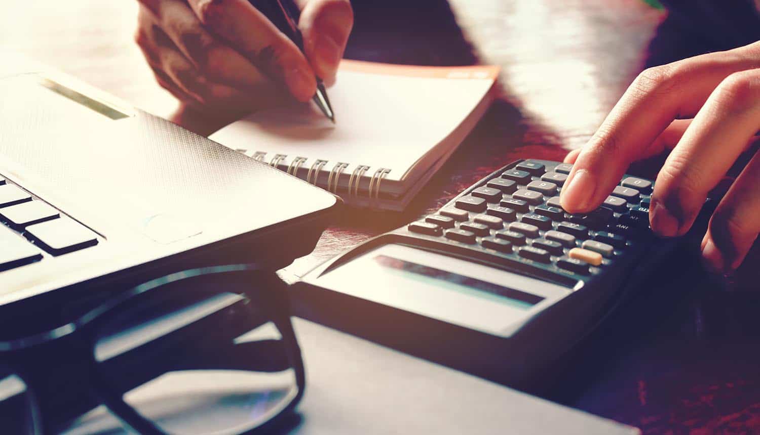 Hand using calculator showing ransomware attack costs