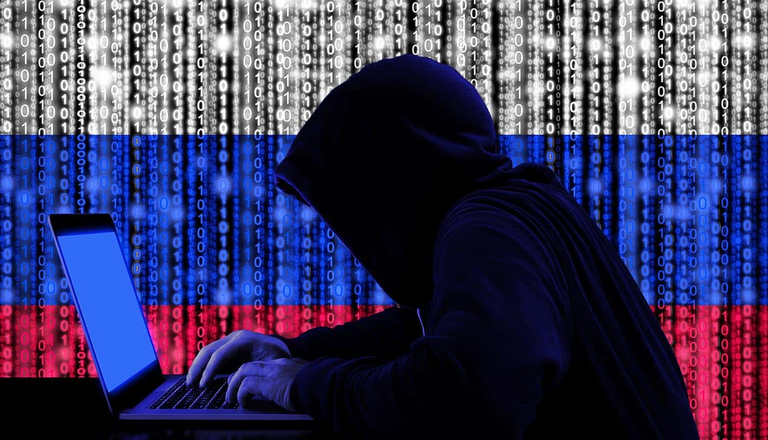 Russian hacker sitting in front of laptop showing security breach