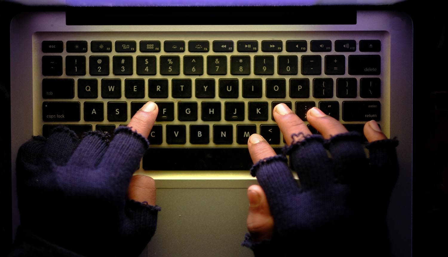 Hacker working on laptop at night showing cyber events top risk
