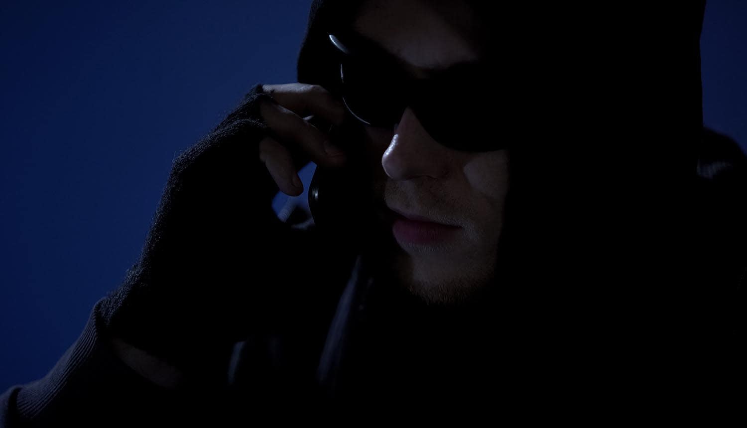 Hacker on phone showing audio deepfake and voice phishing