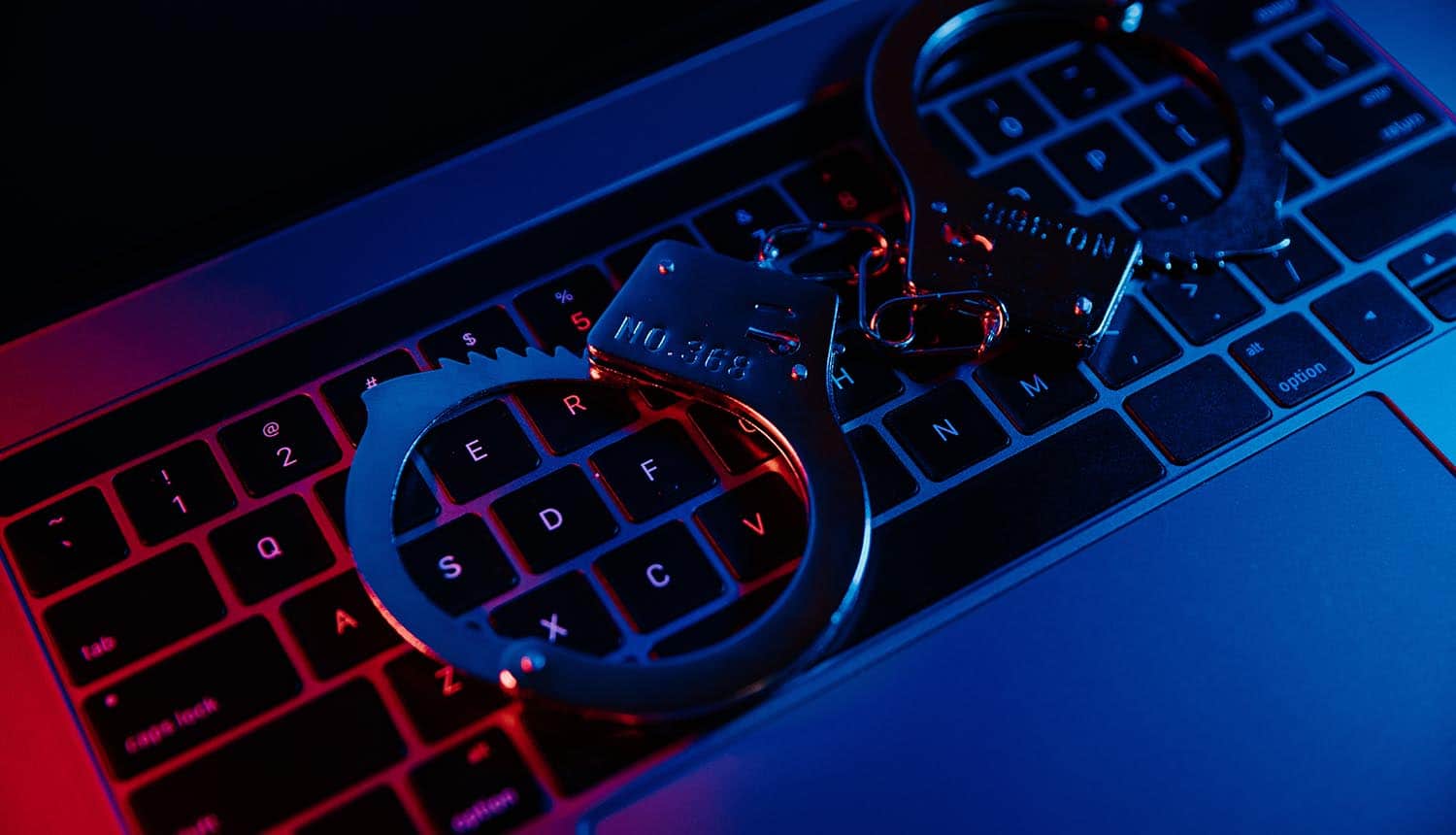 Handcuffs on keyboard showing law enforcement operation on botnets
