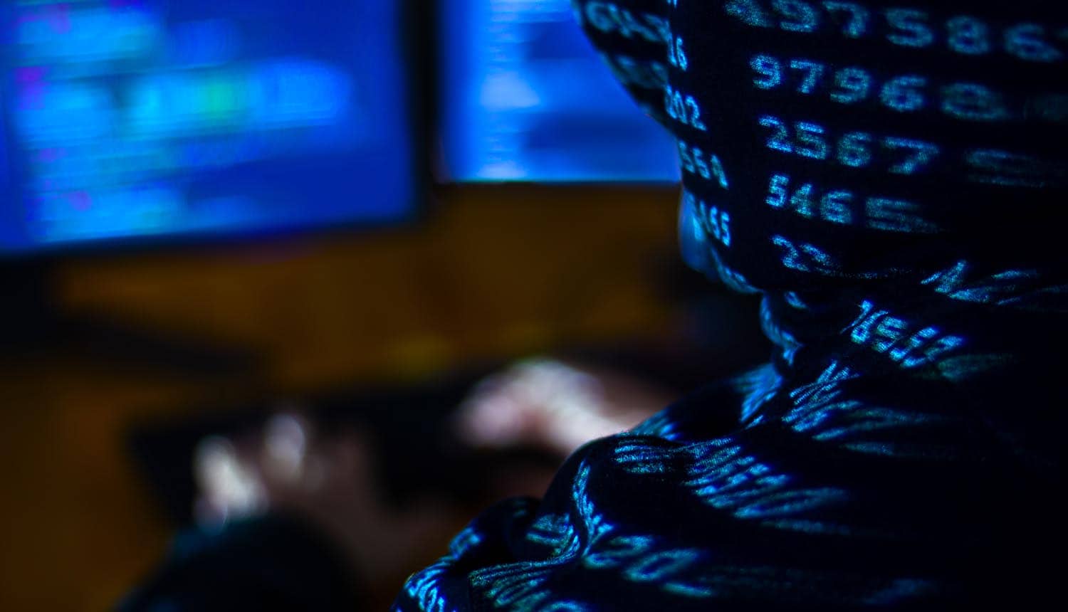 Man in hood typing on keyboard showing Pokémon developer data breach