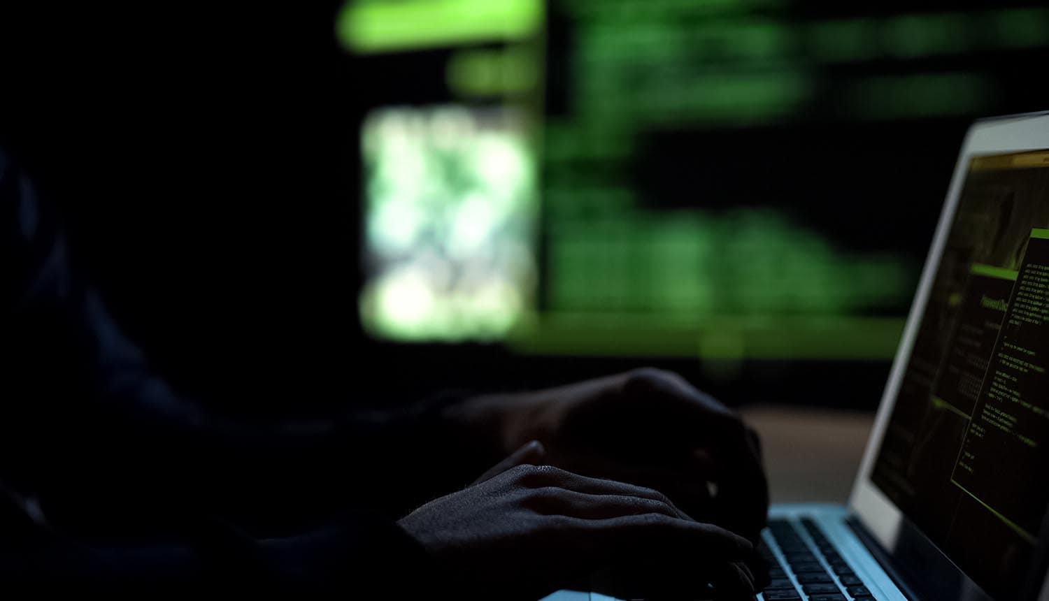 Hacking group member working on laptop