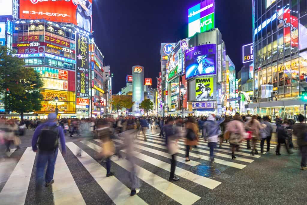 Pedestrians at Shibuya crosswalk showing cyber attacks prompt national emergency