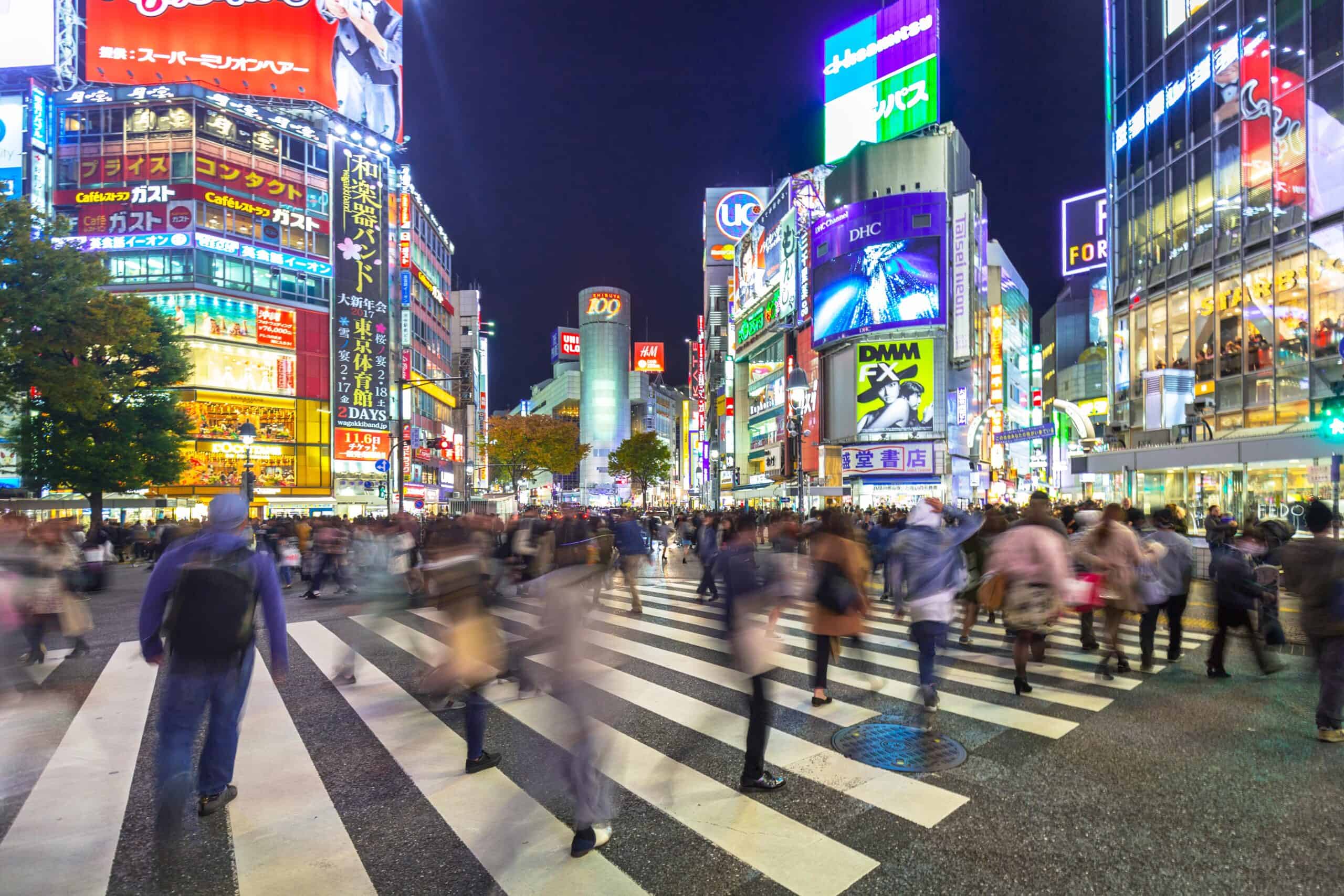 Pedestrians at Shibuya crosswalk showing cyber attacks prompt national emergency